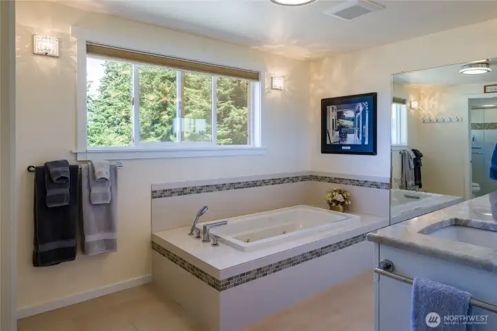 Primary bathroom with spa tub and double vanity sinks.  Just out of sight to the left is the glass fronted shower.