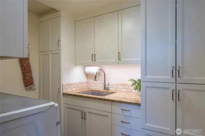 Laundry room with deep sink and folding area across the top of the washer/dryer to the left.