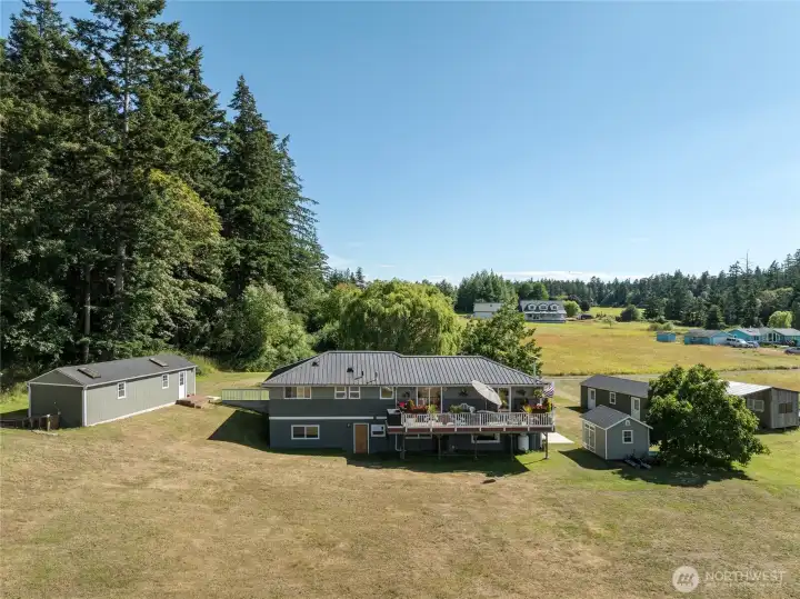 14ft by 40 ft outbuilding on left, house center, garden shed, second 14ft by 40 ft outbuilding and barn on far right.