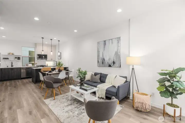 Sun-filled living room with wide plank floors and oversized windows that showcase the energy of the neighborhood while filling the interior with natural light.