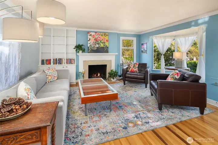 Living room features wood burning fireplace, built in book shelves, and large bay window