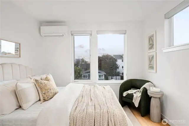 Corner primary bedroom with hardwood floors and lots of natural light.