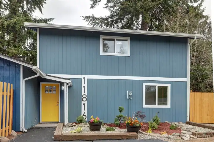 Modern blue exterior with crisp white trim, a bold yellow entry door, and refreshed low-maintenance landscaping for standout curb appeal.