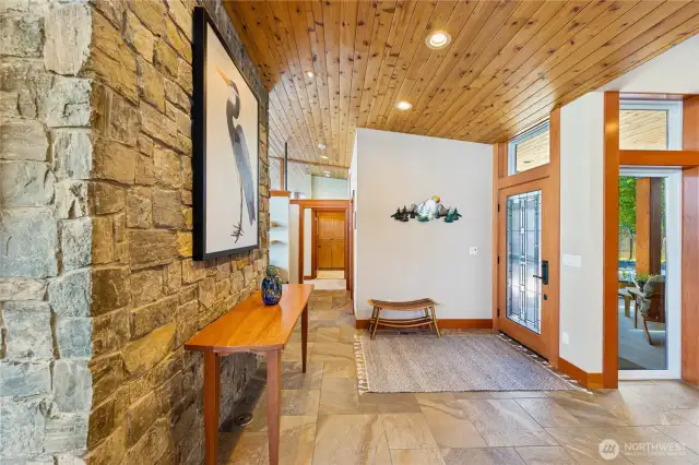 Backside of the large stone fireplace creates a stunning art wall; hallway leading towards the owner's retreat space.