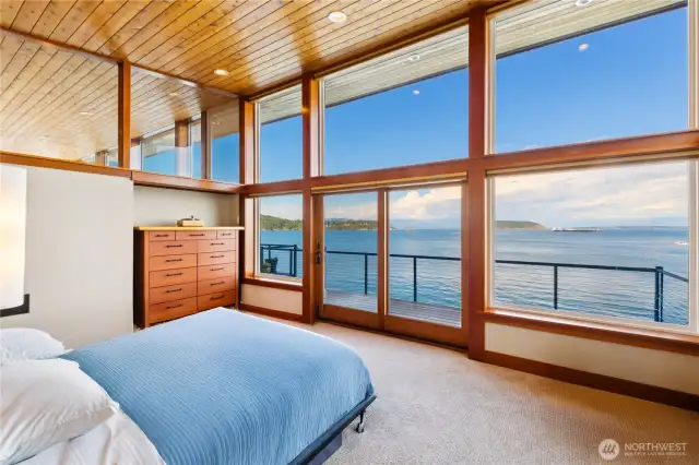 Owner's suite with stunning views and a wall of windows looking towards the water. Custom designed windows connect the owner's suite into the main living area creating a dramatic impact with the seamless wood ceiling.