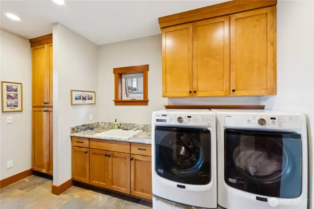 View of main level laundry with utility sink and additional cabinet space.