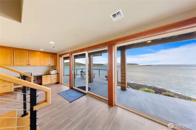 Downstairs is accessed via beautiful wood steps leading to large multi purpose flex space perfect for home office, recreational room, home gym and more. Glass doors lead out to the covered waterfront space.