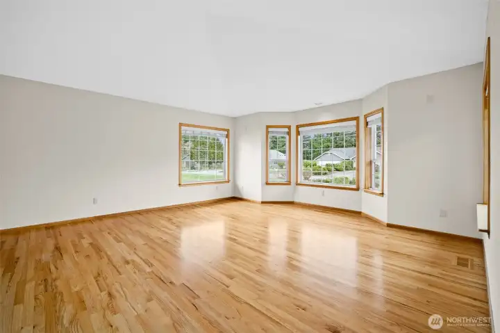 Living room located to the right of the entry featuring hardwood floors and multiple windows providing natural light.