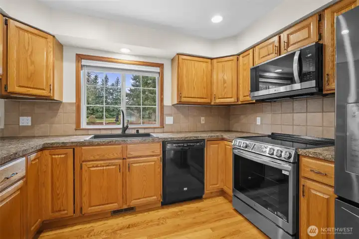Alternate kitchen view showing additional counter space, tile backsplash, and stainless steel range and microwave.