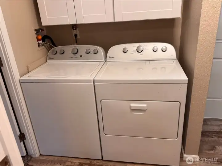 Dedicated laundry space with storage above.