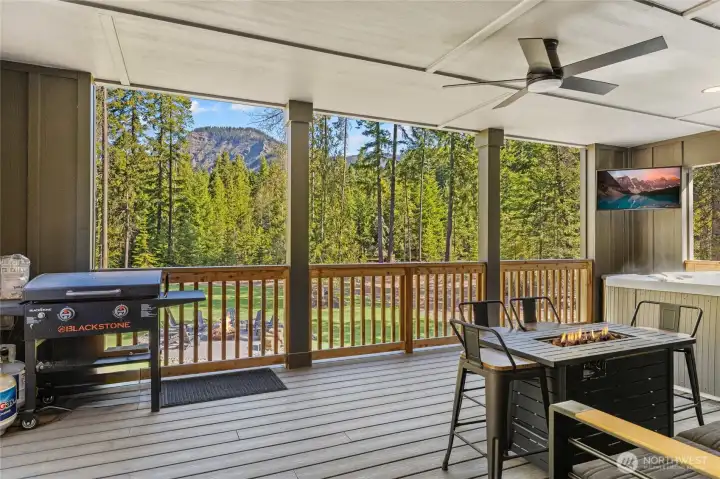 View from deck overlooking the beautiful yard and picturesque mountain views. You ca sit by the fire on the deck or have a fire in the large outdoor fire pit. If you'd rather soak in the hot tub and watch some TV - that is also your option