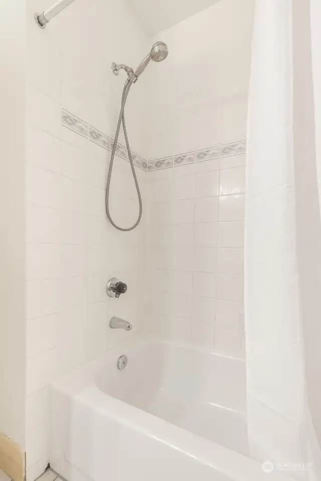 Full bath with tub and tile surround.