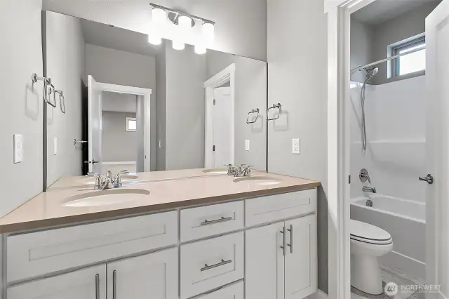 A spacious upstairs bathroom featuring double sinks and a designated area for the toilet and shower, ensuring functionality and privacy.