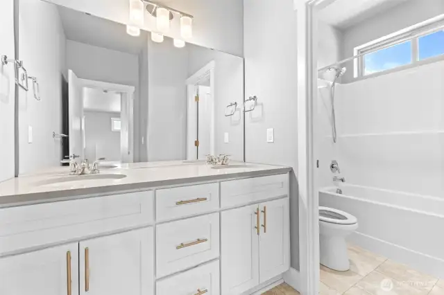 A spacious upstairs bathroom featuring double sinks and a designated area for the toilet and shower, ensuring functionality and privacy.