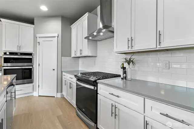 Gas oven paired with sleek hood vent and a stylish tile backsplash