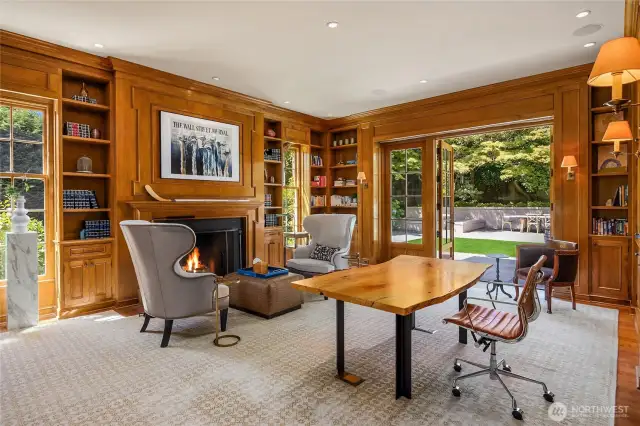 The office/den is fully paneled with tons of built-in bookshelves and storage cabinets.  French doors again open to the garden ouside and notice there is a fireplace on the back wall.