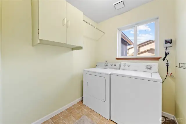 Laundry room with cabinets for extra storage and a convenient clothes rod. Washer and dryer stay with the home.