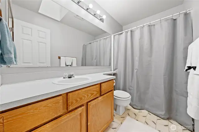 Upstairs full sized guest bathroom with tub/shower combo with a skylight that brings in lots of natural light.