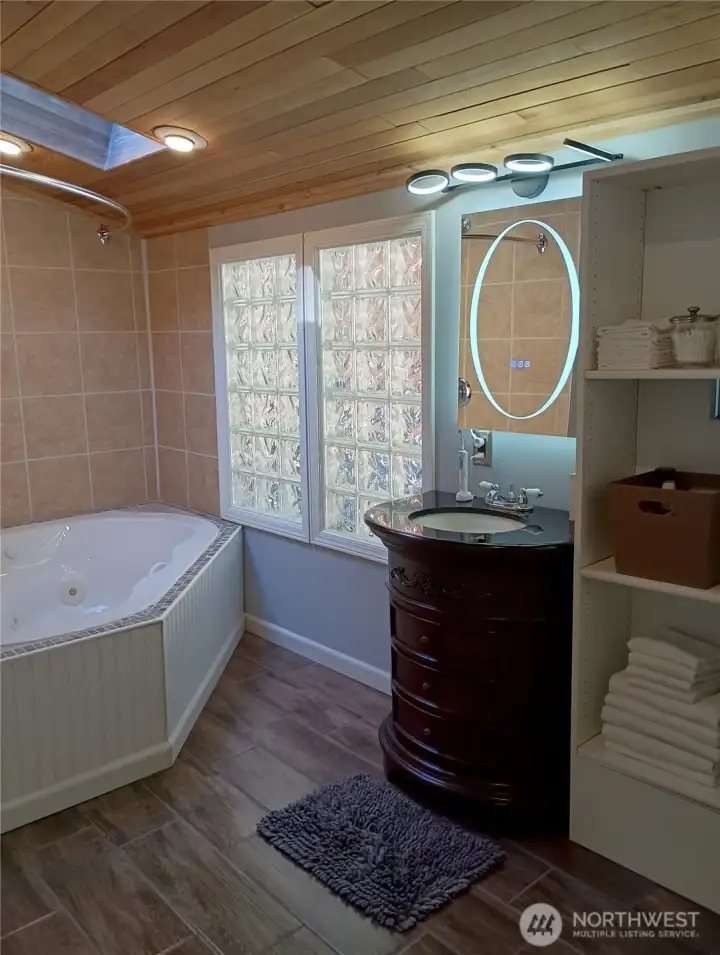 Primary en suite bathroom with jetted corner tub, cedar ceilings and skylight..