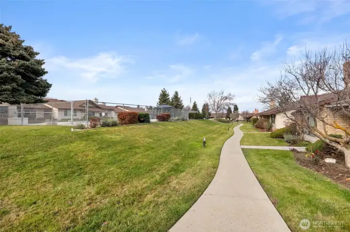 Common area with sidewalk and gated outdoor pool.