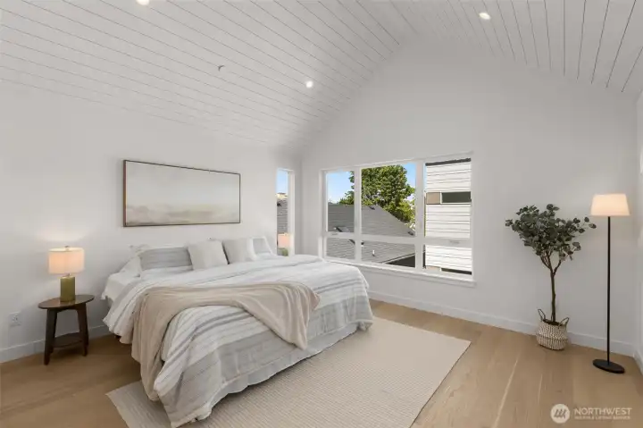 The primary suite is a true retreat, featuring vaulted ceilings and large windows that frame the neighborhood views.