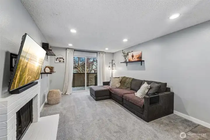 Large living area looks out to private balcony with trees and green space