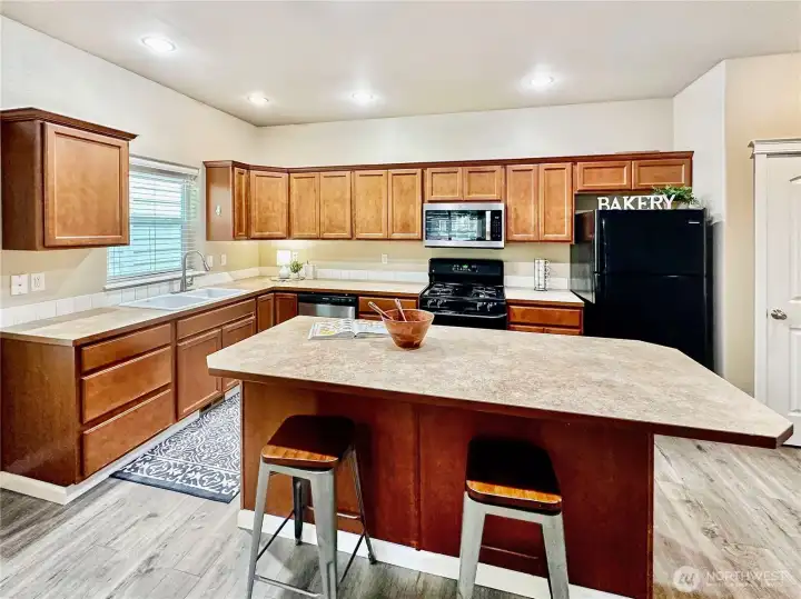 Ample kitchen with loads of cabinets and counter space, island with eating bar, pantry, laminate flooring and all appliances.