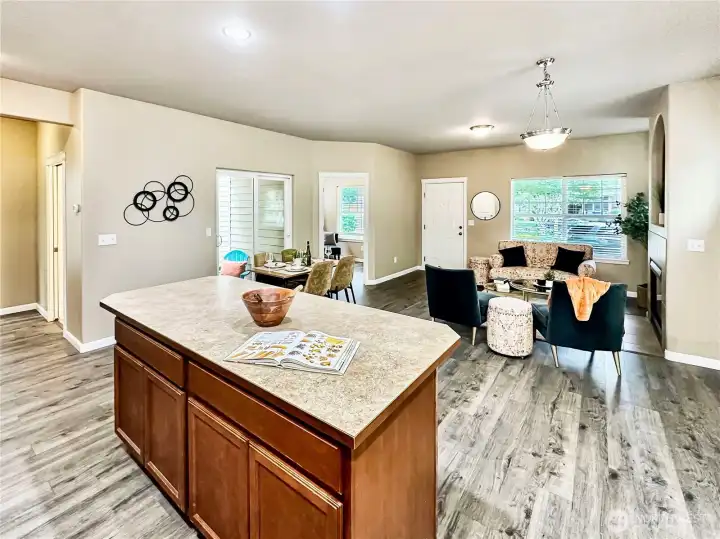Looking across the eating bar from the kitchen.  In this photo you see the slider access to the covered side patio, door way to the den/office, living/dining areas and hall that leads to the powder room and upper floor.