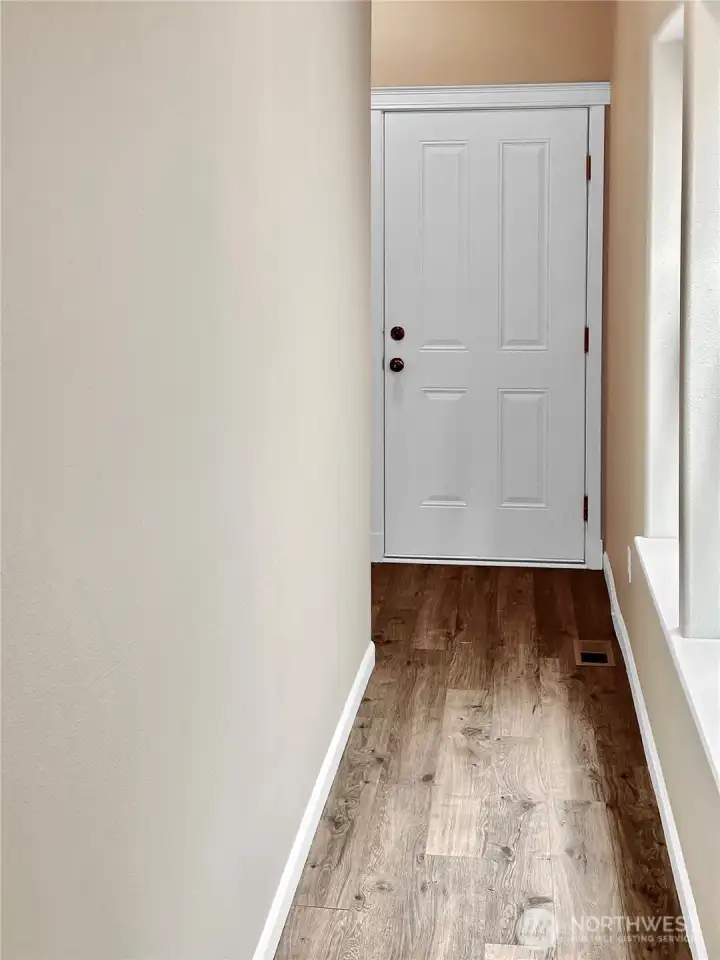 This is a photo of the hall that leads to the back yard and attached 2 car garage.  The hall offers natural light with several west facing windows.