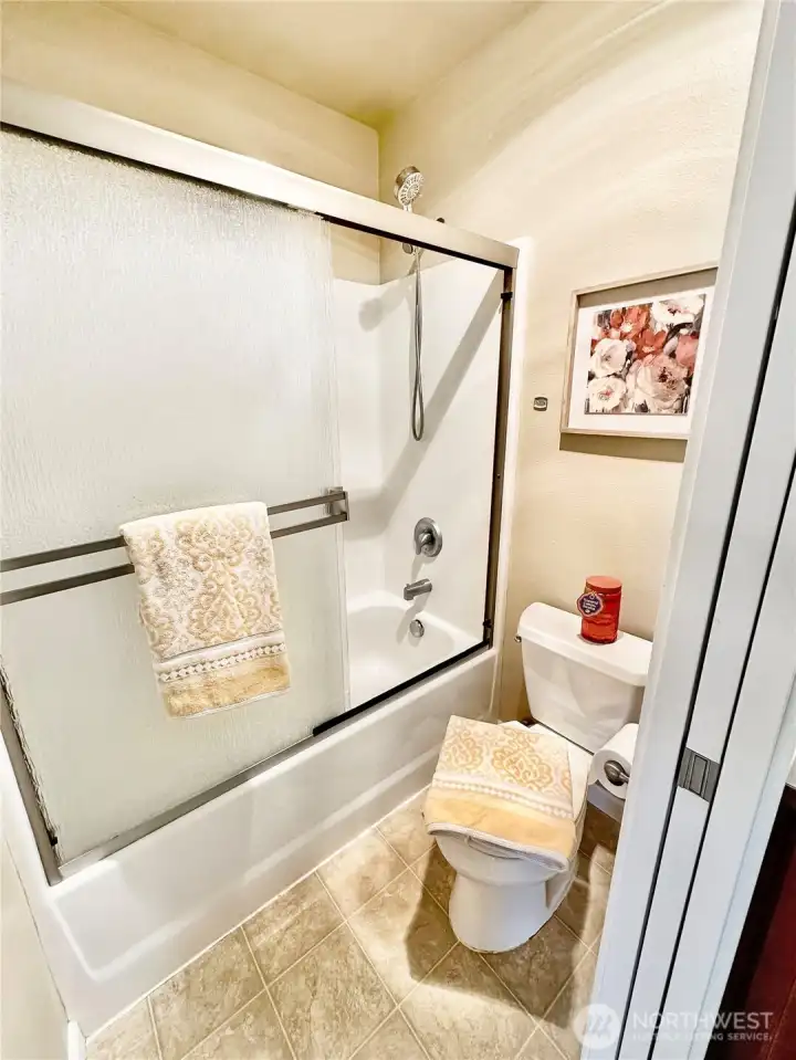 Primary tub/shower, toilet area with pocket door for privacy.