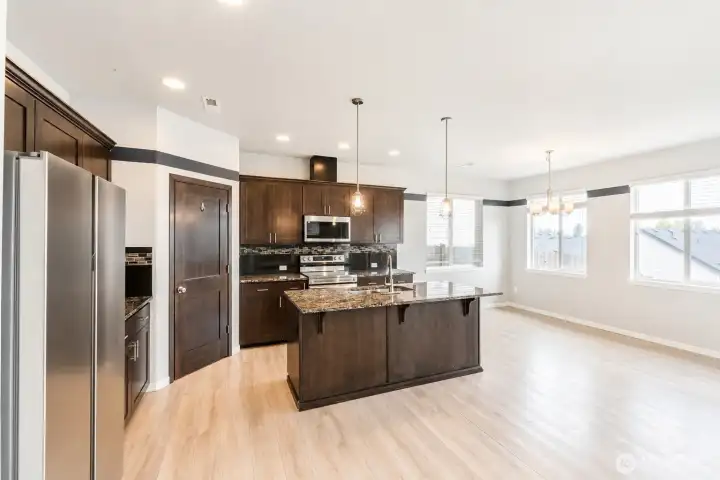Gourmet kitchen featuring a large center island, stainless steel appliances, abundant cabinetry, and an open-concept design.