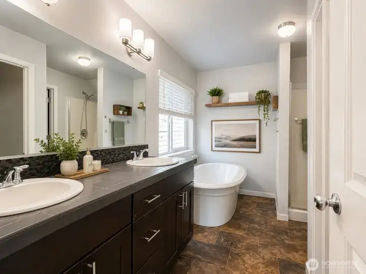 Spacious primary bath featuring dual vanities, a soaking tub, and a walk-in shower