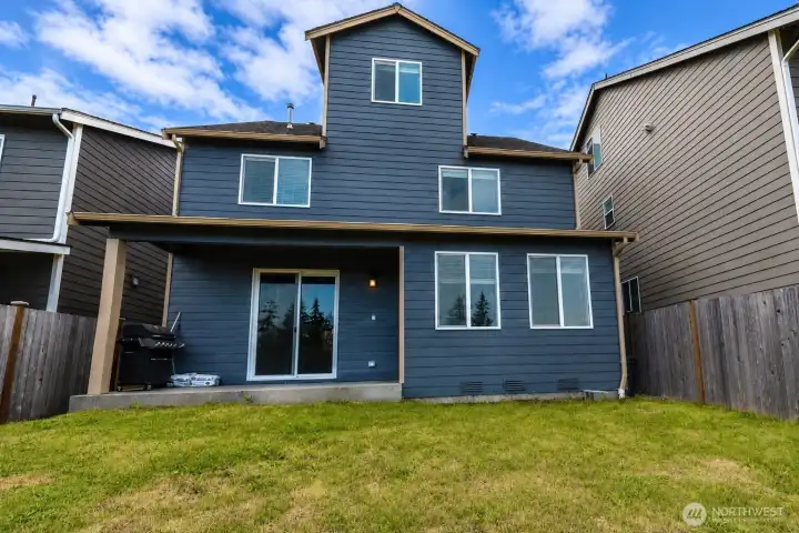 Rear exterior showcasing the covered patio and fully fenced backyard.