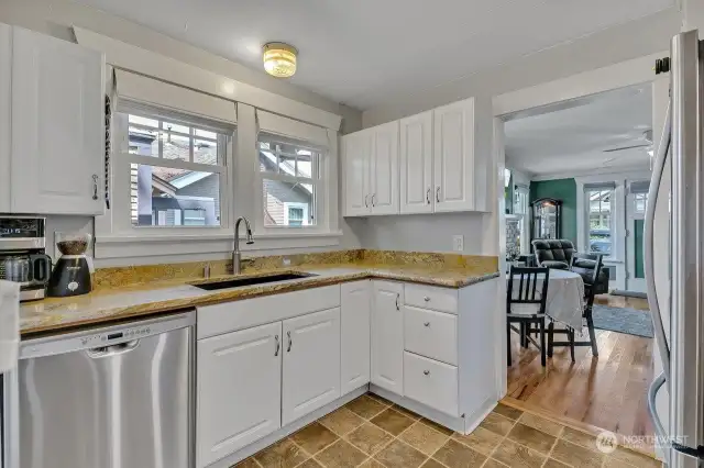 The light-filled kitchen offers stainless steel appliances, including a new sink, vent hood, and a newer refrigerator, complemented by granite countertops and a built-in garbage disposal and dishwasher.