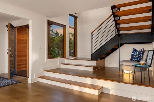 Architecturally interesting steel stairs with large windows lead with outdoor light from main to upper level.
