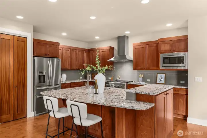 The gourmet kitchen offers granite countertops, premium cabinetry, a 6-burner range and impressive oversized island