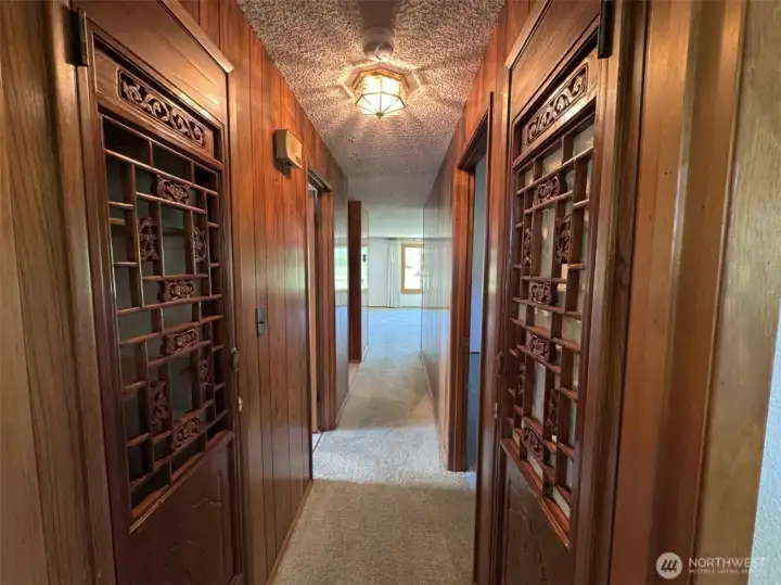 Hall from second bedroom, looking to living area--linen closets on either side of hall, with carved doors.