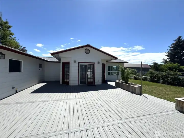 Deck from rec room to the swim spa and hot tub wing. This room can also be entered from the garage.  Planter box to the right is filled with black raspberries.  There is another planter box outside of view, ready for your plantings!