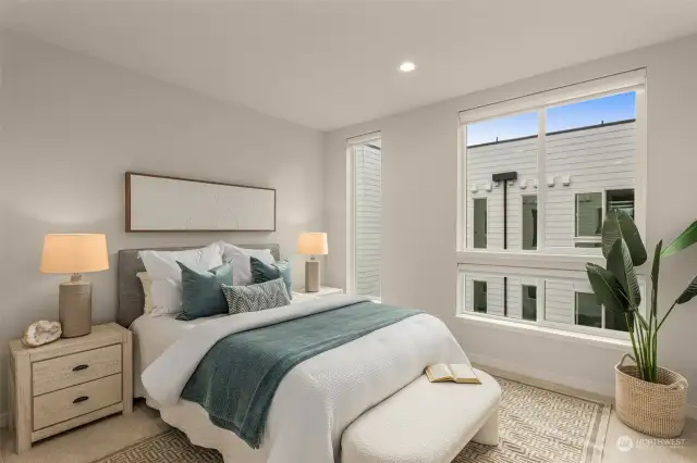 This bright, airy bedroom offers a warm ambiance with large windows. It's a versatile space designed for comfort, perfect for guests or as a personal retreat.