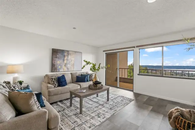 Expansive windows flood the space with natural light and frame spectacular views of Day Island, Fox Island, and the Tacoma Narrows—especially breathtaking at sunset when the sky reflects golden hues over the water.