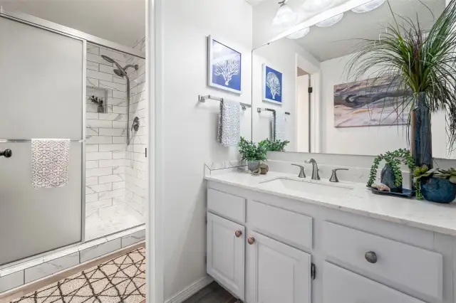 The ensuite bathroom has been updated with modern fixtures, fresh tilework, and soft lighting, creating a calming and luxurious feel.
