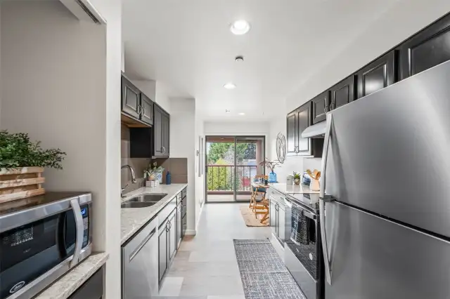 The kitchen features new stainless steel appliances, a modern sink fixture, and sleek countertops that combine both style and functionality.