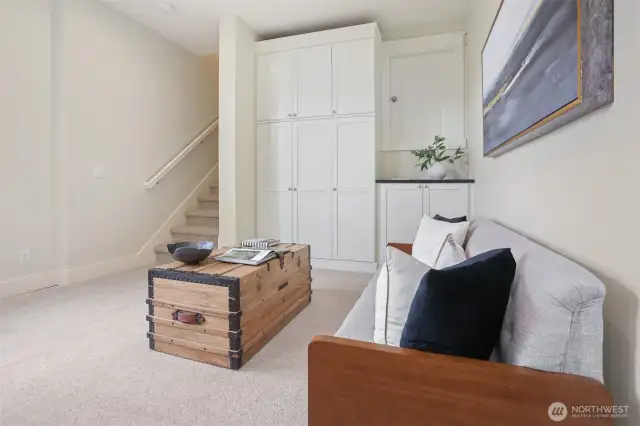 Daylight family room with built in cabinets, tall ceilings, and door to secret bonus storage.