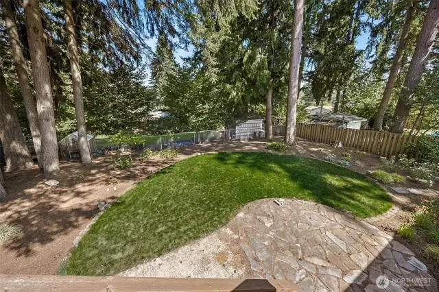 Deck view of the back yard with a good mixture of grass, natural landscape and a paved area too!