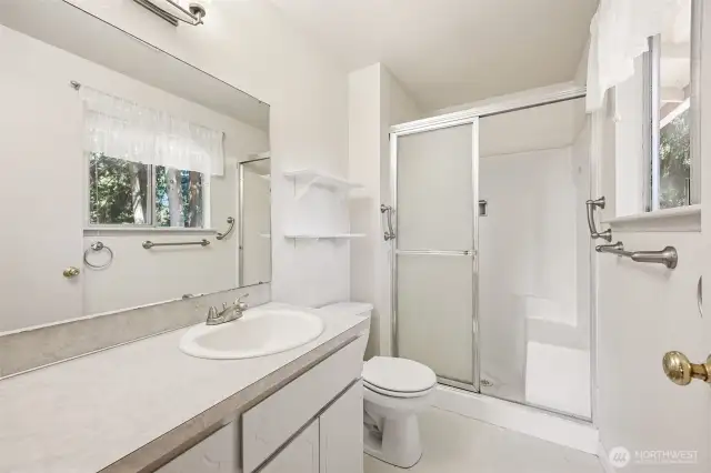 Light and bright primary bath has a shower with a bench seat in it.