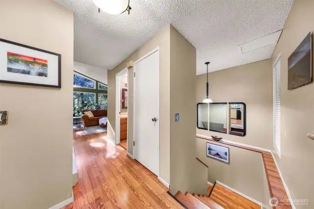 View from main entry to living, bathroom and stairs to lower level