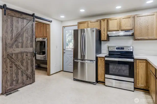 Barn door opens to half bath with laundry hookups.