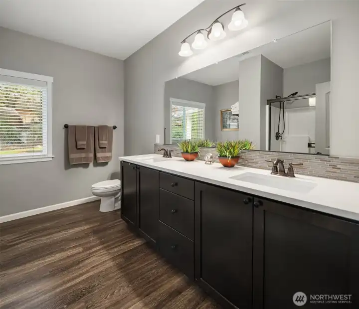 The ensuite bath features a dual-sink vanity, rich cabinetry, and subtle finishes.