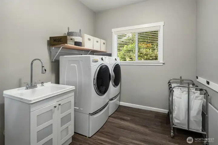 The laundry room offers thoughtful organization, modern appliances, and a window view that brings a touch of nature to everyday tasks.