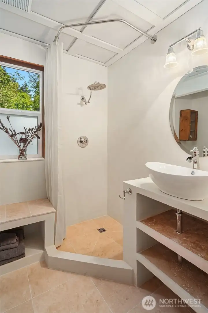 Newly renovated 3/4 bath on the main level with travertine floors, plaster walls and custom vanity.